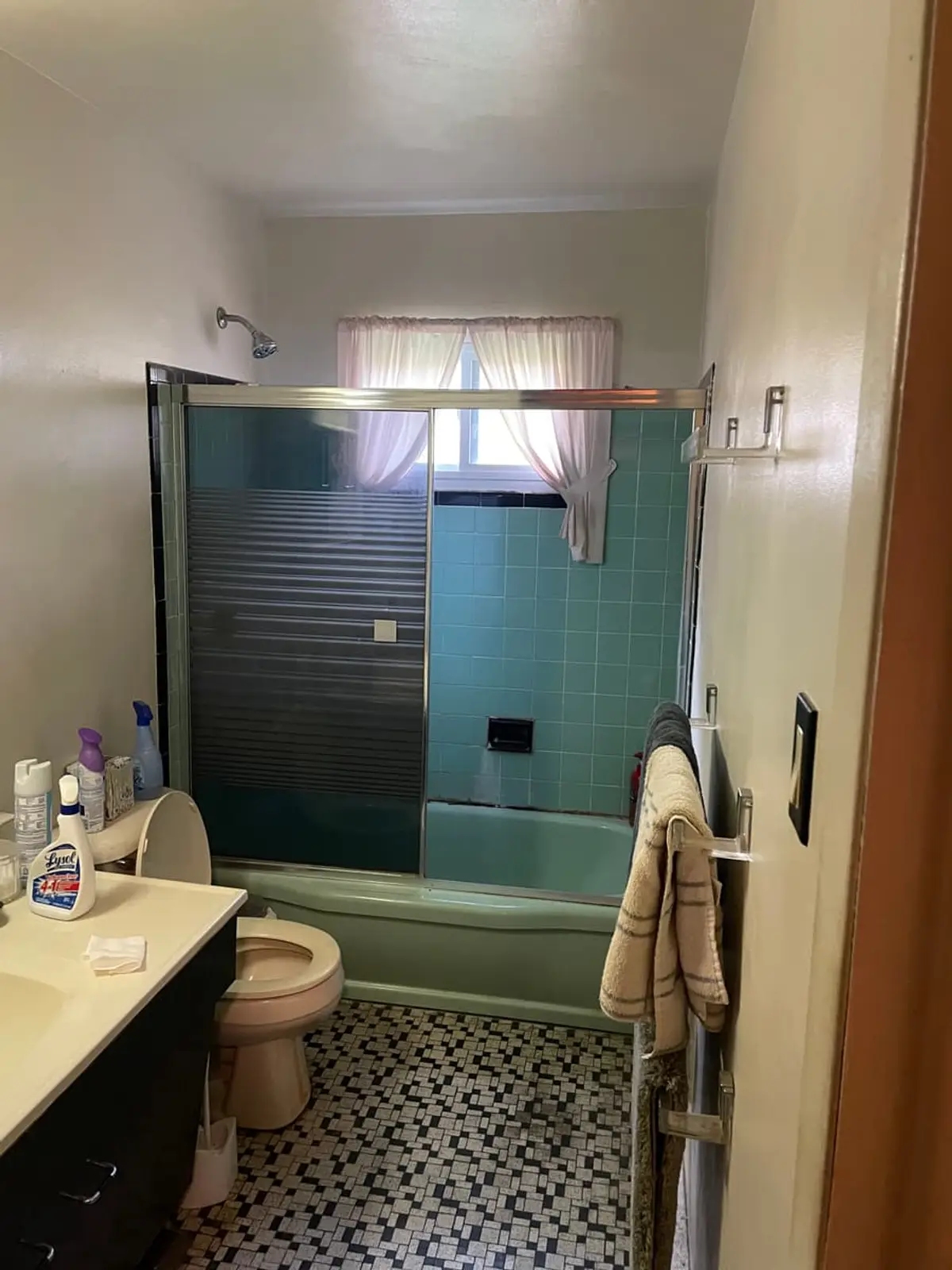 Selling a water-damaged house in Babylon: dated bathroom with a teal tub and mosaic floor tile