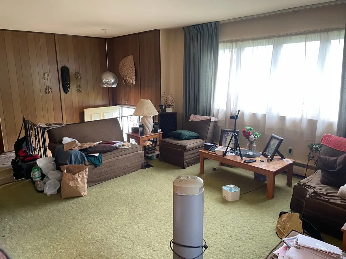 Selling an inherited house in Babylon: living room with green carpet and furniture left in place