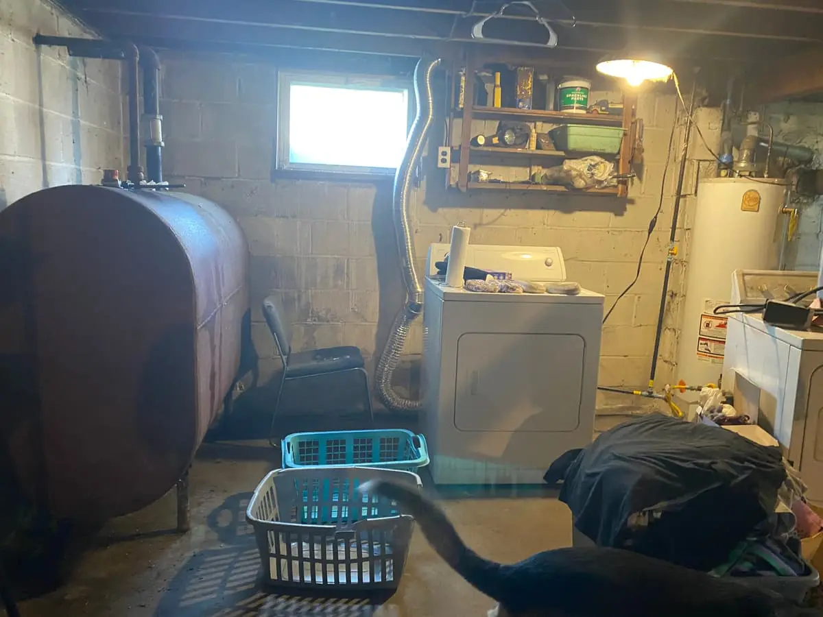 Selling a house with an oil tank in Babylon: old oil tank beside a washer in a cluttered basement
