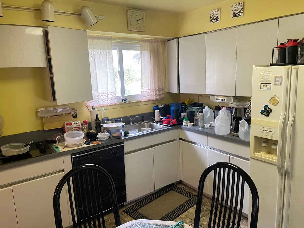 Selling a house with a reverse mortgage in Babylon: yellow kitchen with white cabinets and a cluttered dinette